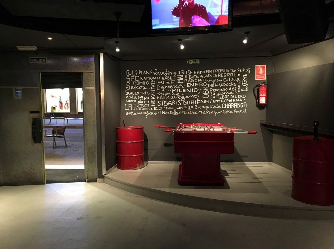 Mur cal·ligràfic amb noms de músics darrere del futbolí del local Milenio de Sant Feliu